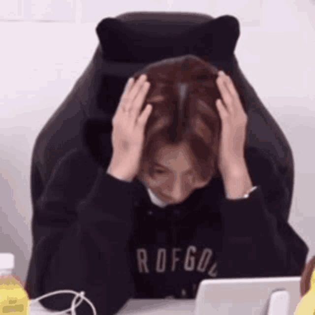 a woman is sitting in a chair holding her head .