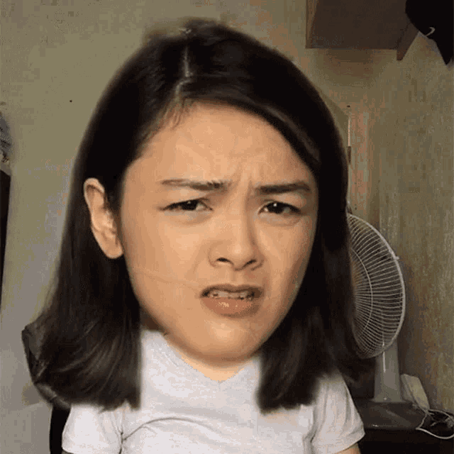 a woman with a big head making a funny face in front of a fan
