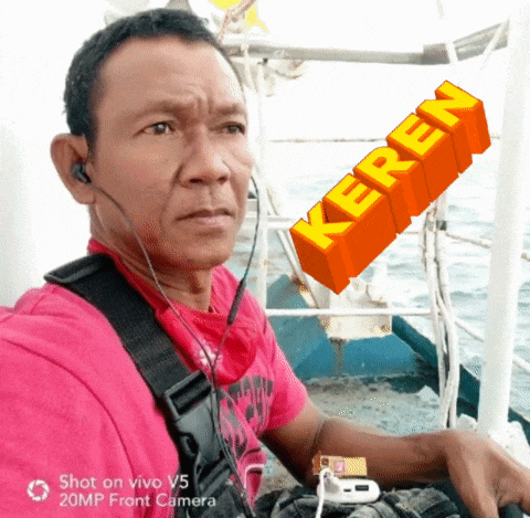 a man wearing ear buds and a pink shirt with the word keren on the bottom right