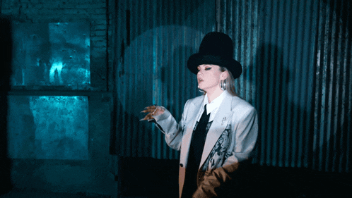 a woman in a top hat is standing in front of a wall