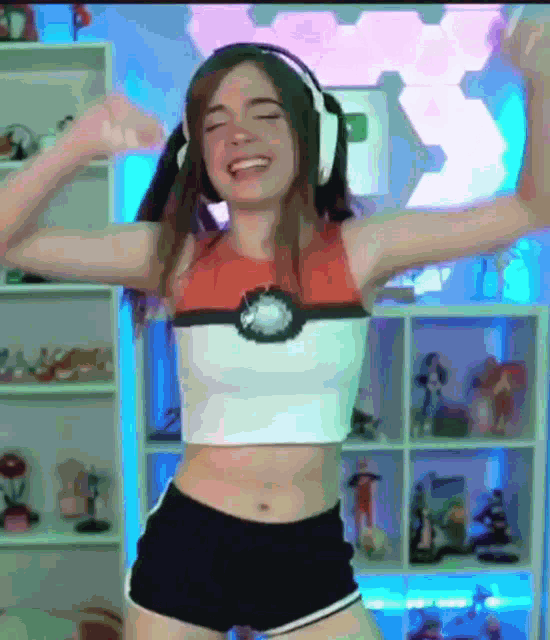 a woman wearing headphones and a crop top with a pokeball on it is dancing