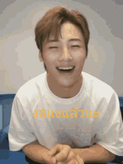a man wearing a white shirt with the word john on it is laughing