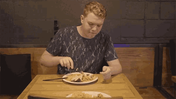 a man is sitting at a table eating a plate of food