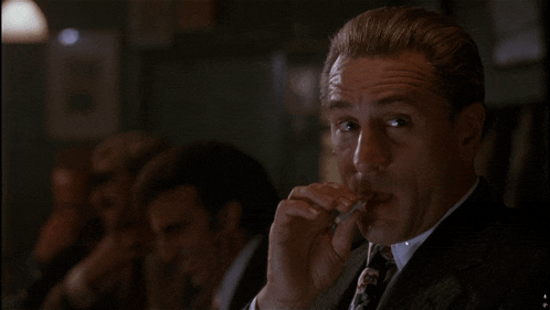 a man in a suit is smoking a cigarette