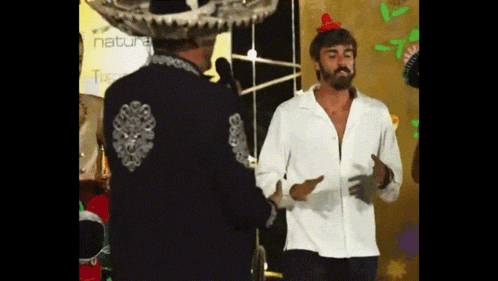 a man wearing a sombrero stands next to another man in a white shirt
