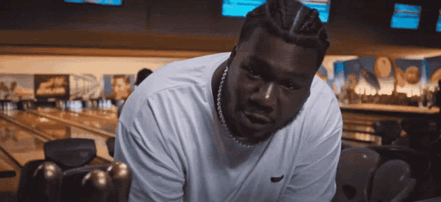 a man in a bowling alley is wearing a white nike shirt