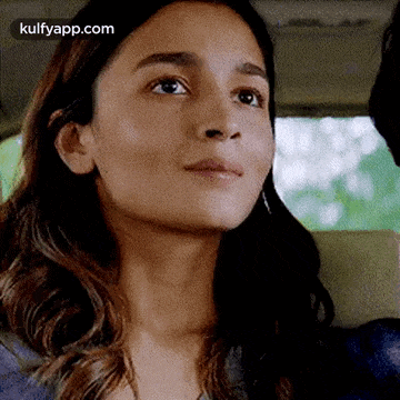a woman is sitting in the back seat of a car and looking up .