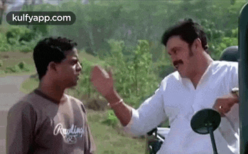 two men are standing next to each other in a field and talking .