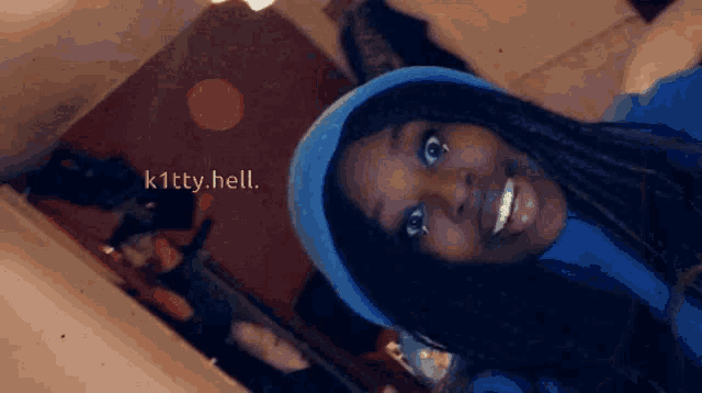 a woman wearing a blue hat is smiling with the words k1tty.hell written on the bottom