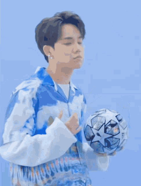 a man in a blue shirt is holding a soccer ball in his hands