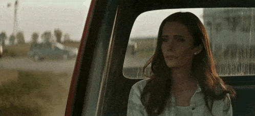a woman is sitting in the back seat of a truck looking out the window