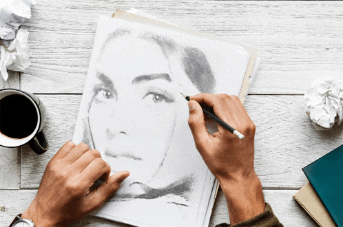a man is drawing a woman 's face with a pencil on a piece of paper