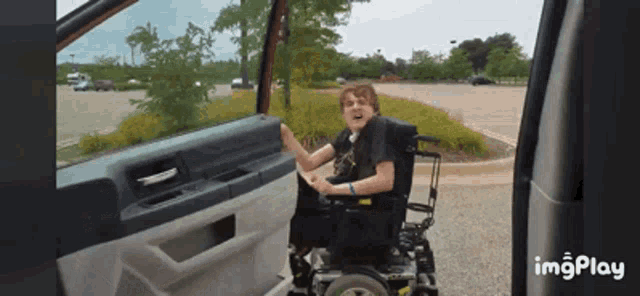 a man in a wheelchair is sitting in the driver 's seat of a car with imgplay at the bottom