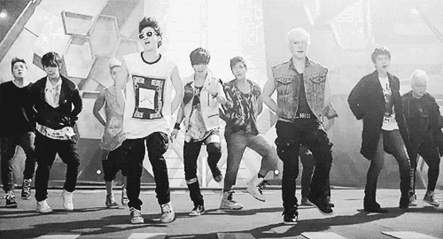 a black and white photo of a group of young men dancing together .