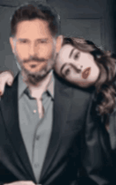 a man and a woman are posing for a picture and the woman is leaning on the man 's shoulder