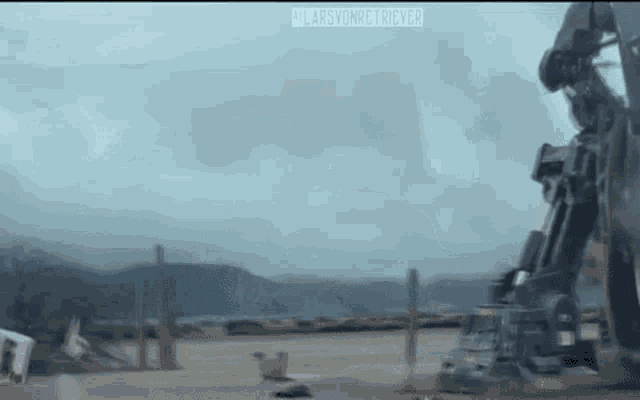 a robot is standing on top of a dirt field in a field .