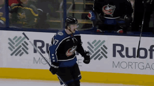 a hockey player stands on the ice in front of an ad for rubf mortgage