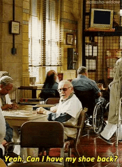 an elderly man in a wheelchair is sitting at a table in a nursing home and asking if he can have his shoe back