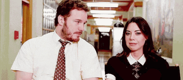 a man and a woman are standing next to each other in a hallway looking at each other .