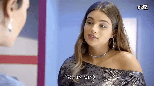 a woman in a velvet off the shoulder top is talking to another woman in hebrew .