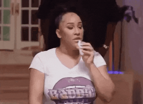 a woman in a white t-shirt is holding a tissue in her hand .