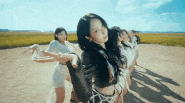 a group of girls are dancing in a field with a blue sky in the background