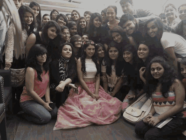 a girl in a pink skirt is surrounded by a group of people