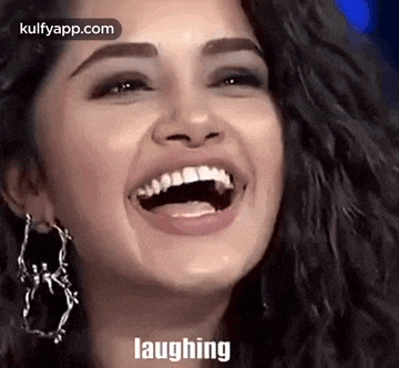 a close up of a woman laughing with her mouth open and earrings .
