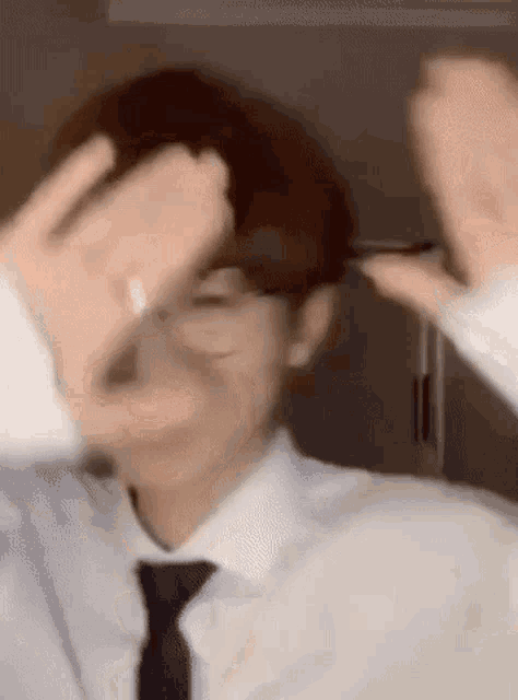 a man wearing glasses and a tie is making a hand gesture .