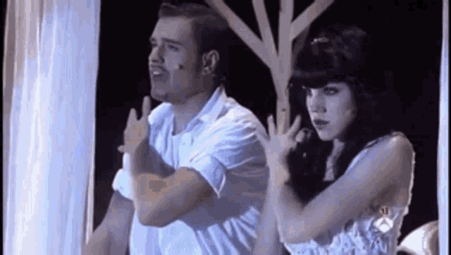 a man and a woman are standing next to each other and the man is giving the middle finger