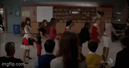 a group of people are dancing in a circle in front of a group of people .