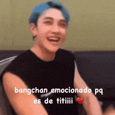 a man with blue hair and a black shirt is laughing and holding a heart .