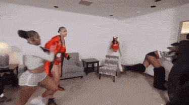 a group of women are dancing in a living room and one of them is wearing boxing gloves