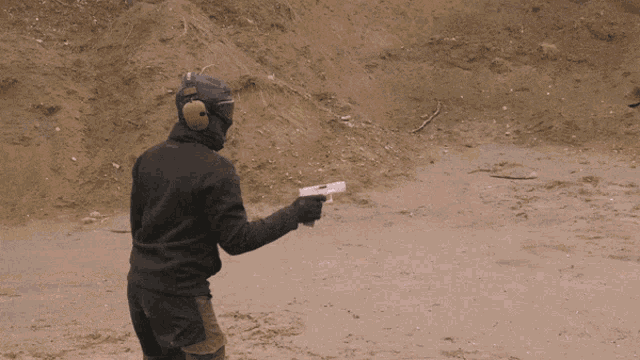 a man wearing a mask is holding a gun in front of a suv