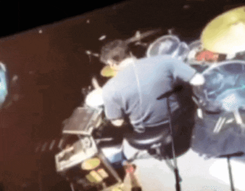 a man in a blue shirt is playing drums