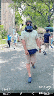 a man wearing a bandana and sunglasses walks down a street on july 14th 2022