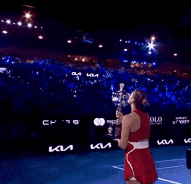 a woman in a red tank top is holding a trophy in her hands