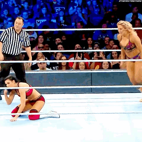a woman is kneeling down in a wrestling ring while a referee watches