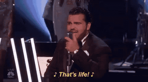 a man in a suit singing into a microphone with the words that 's life