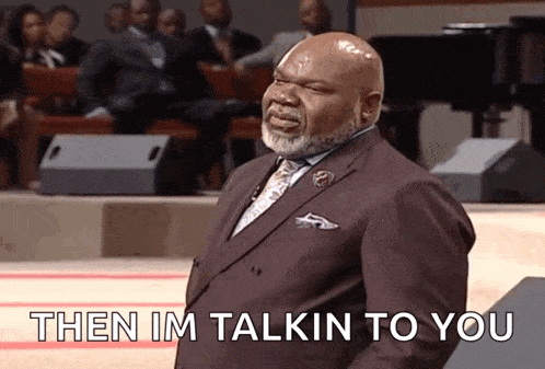 a man in a suit and tie is standing in front of a crowd and says " then im talkin to you "