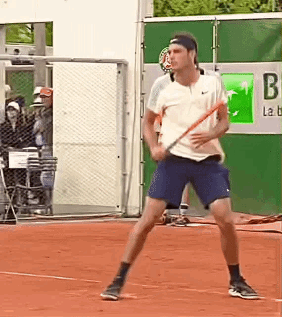 a man is holding a tennis racquet on a tennis court in front of a bnp bank sign .