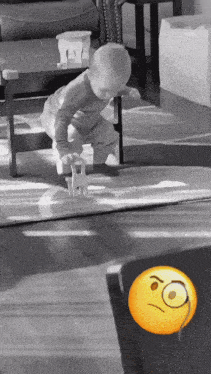 a baby is playing with a toy on the floor and a yellow smiley face appears to be angry