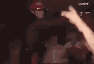 a blurry picture of a man standing in front of a crowd in a dark room
