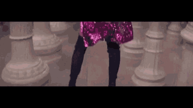 a woman in a pink sequined dress and black thigh high socks is standing in front of a row of columns .
