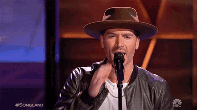 a man singing into a microphone with the nbc logo in the corner