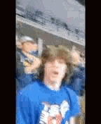 a young man wearing a blue shirt is standing in a crowd .