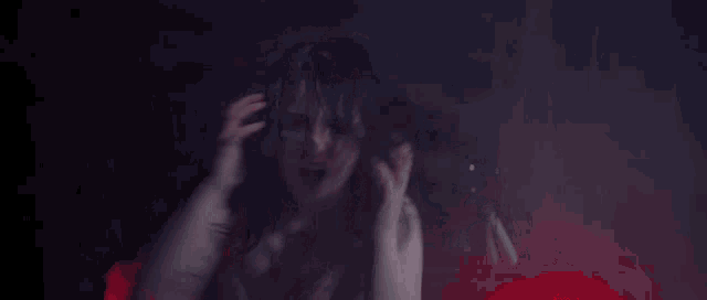 a woman in a white bra is screaming in a dark room with red lights .