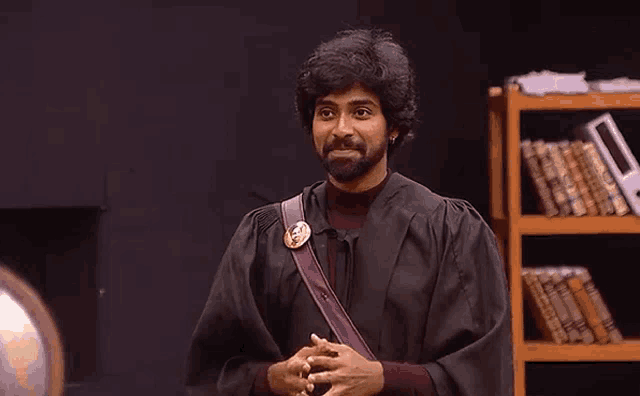a man with a beard is wearing a black gown and a brown strap .
