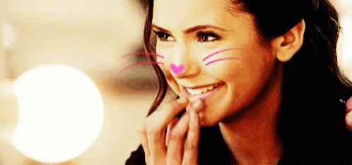 a woman with a cat face painted on her face is smiling and touching her lips .
