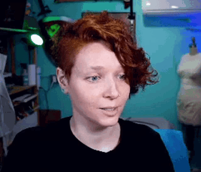 a woman with red hair is wearing a black shirt .